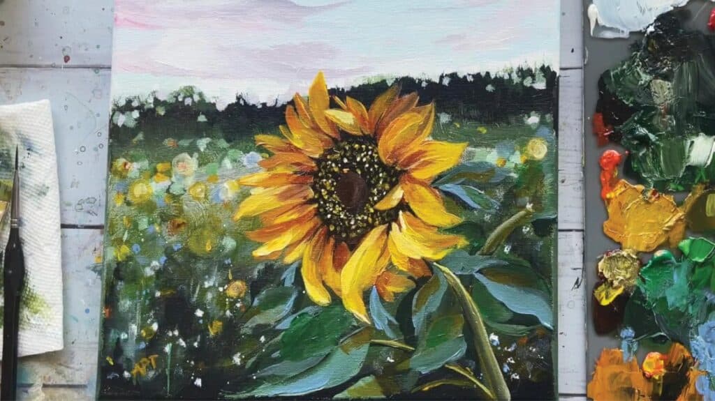 An acrylic painting of a yellow sunflower in the foreground. The background consists of a blurry field of sunflowers, set against a pale blue and light pink sunset sky.