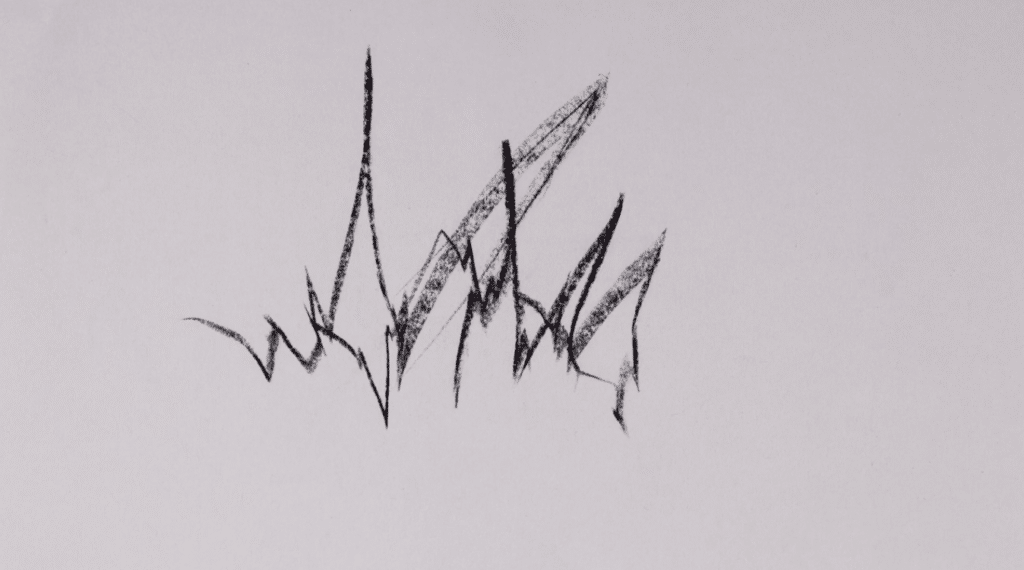 A black scribble is on a white piece of paper. The scribble is made using a black pencil and is spiky and erratic. 