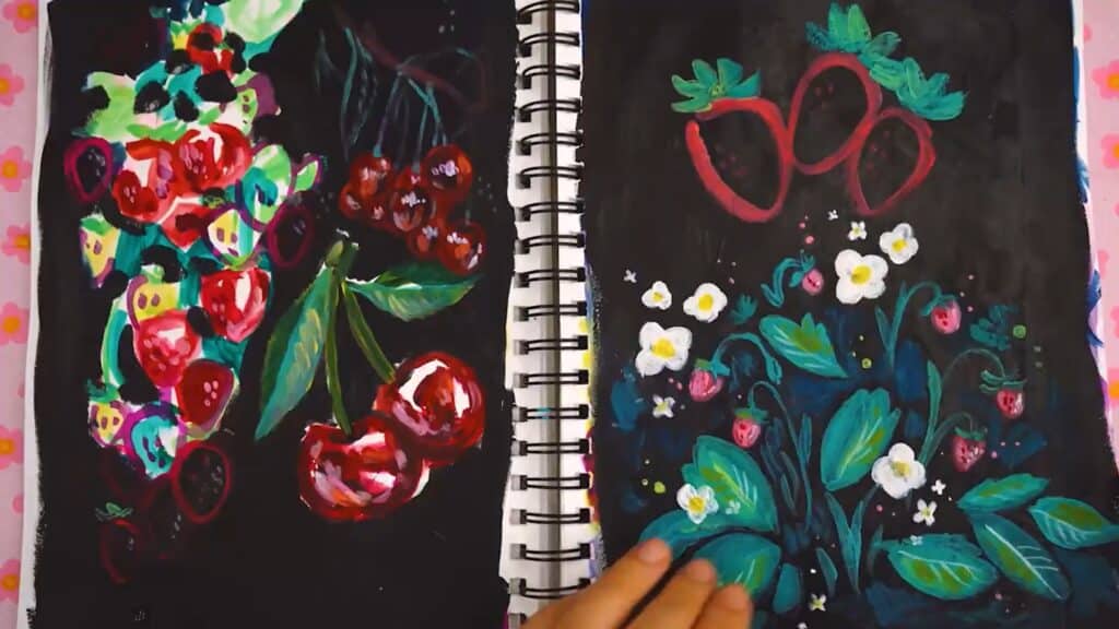 Open sketchbook with pages featuring painted red fruits, including cherries, strawberries and grapes and their leaves, against a painted black background