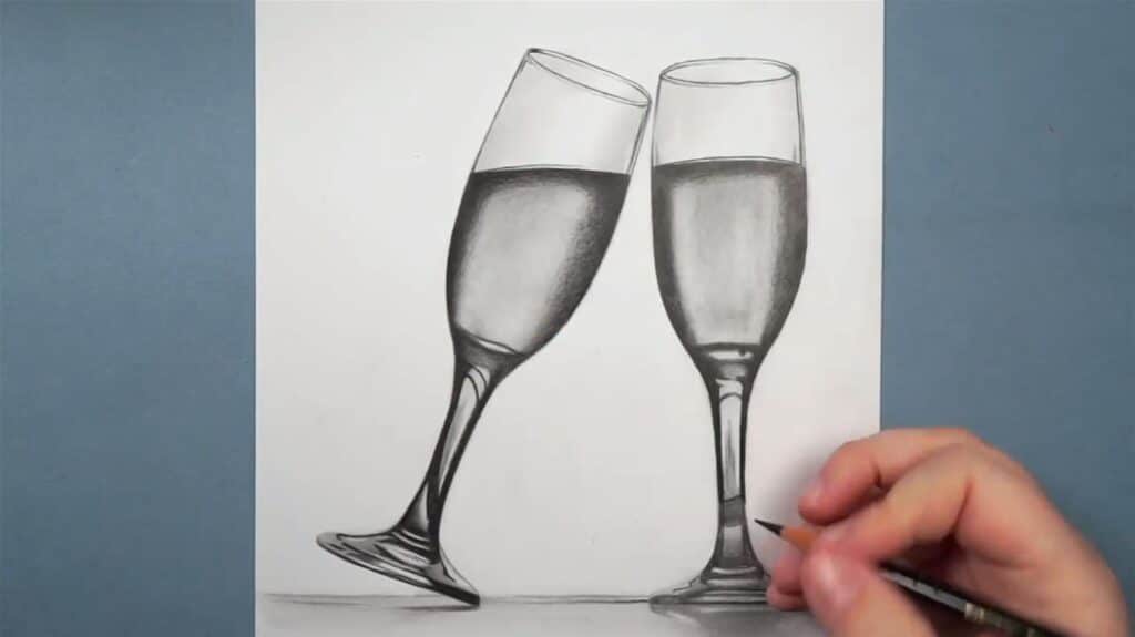 Artist drawing two highly realistic white wine glasses in pencil on white paper, with one of the glasses tilting over as if to “cheers” with the other