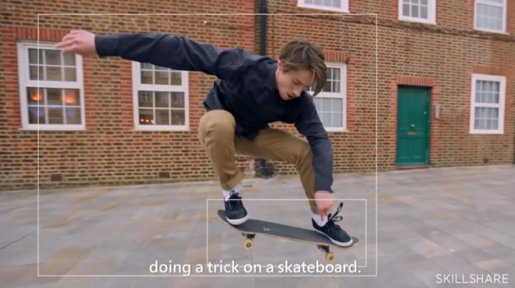 Alt: A photo of a man doing a trick on a skateboard. There are two white squares overlaid on top of the image, one around the man and one around the skateboard.