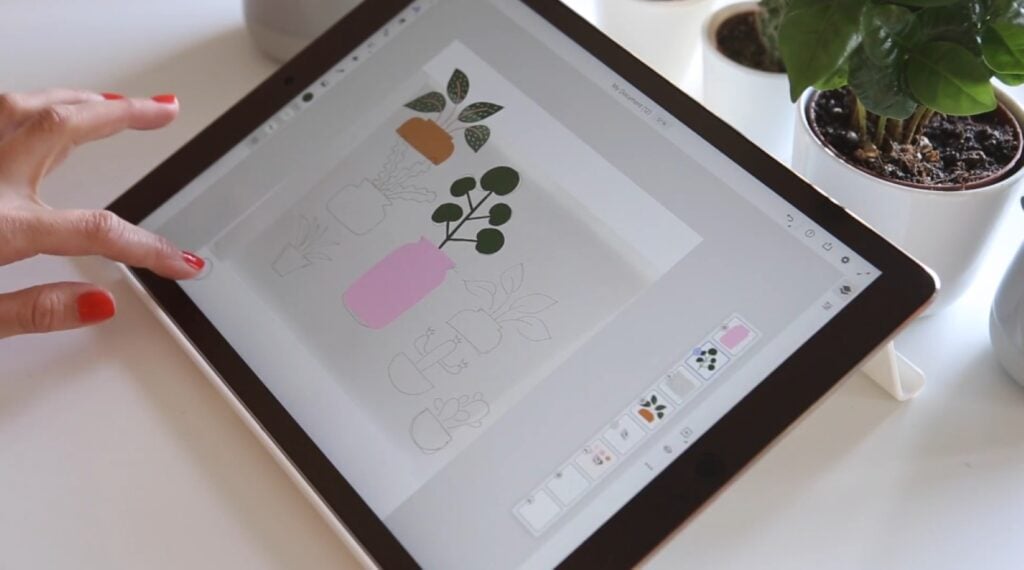 A person’s hand using an iPad app to create a depiction of green plants in various pots. 
