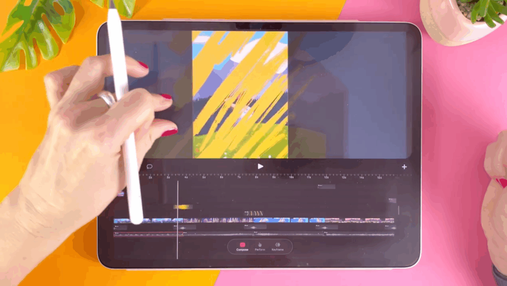 Overhead shot of an iPad with Procreate Dreams 2 open, and a hand holding an apple pencil pinching on the screen