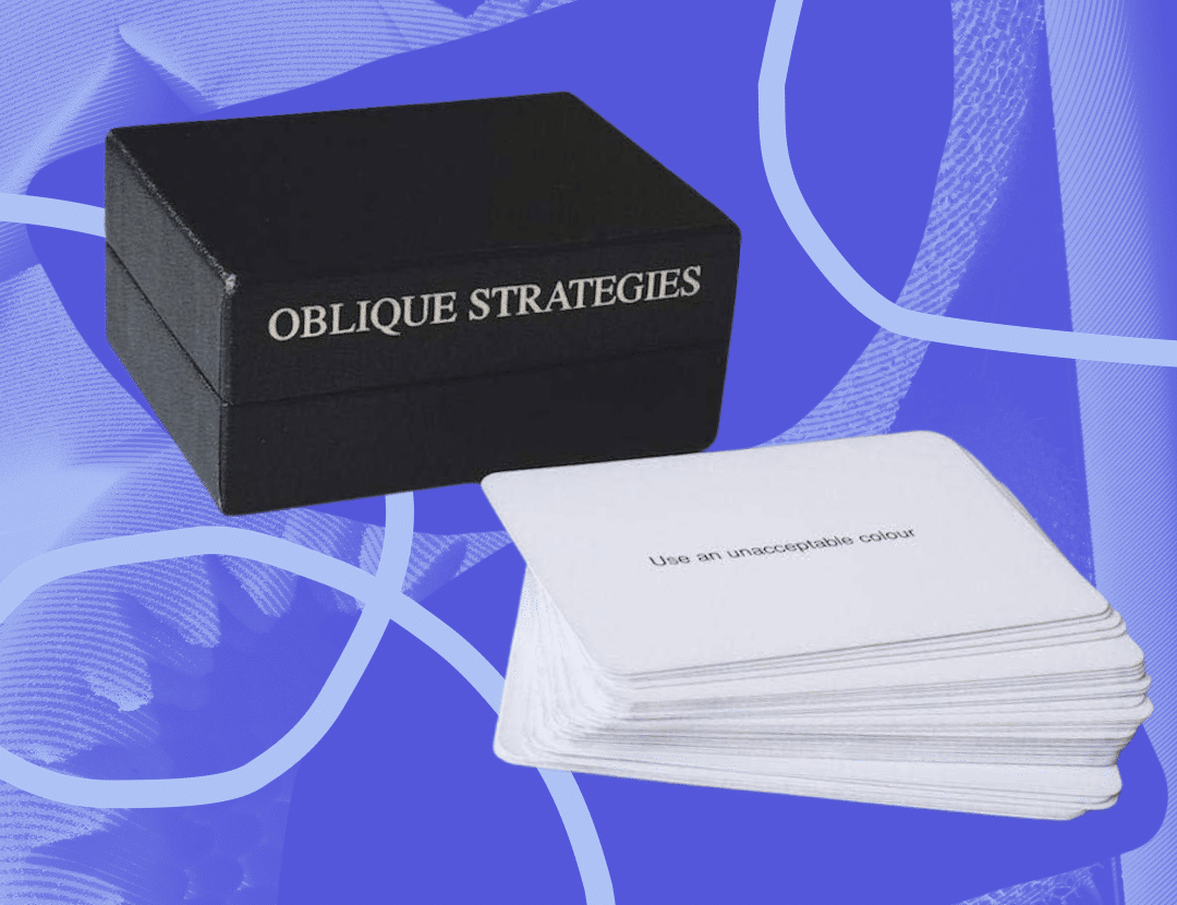 A black box reading "Oblique Strategies" in the background with a deck of white cards with text on them in front